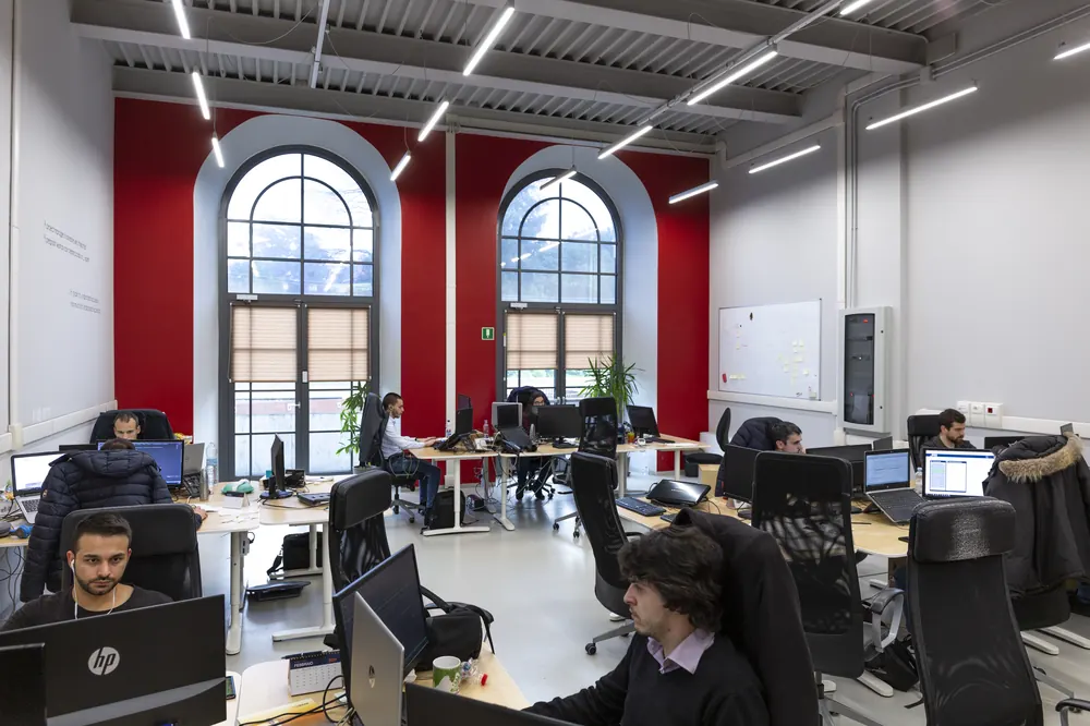 Open space con postazioni di lavoro e pareti rosse